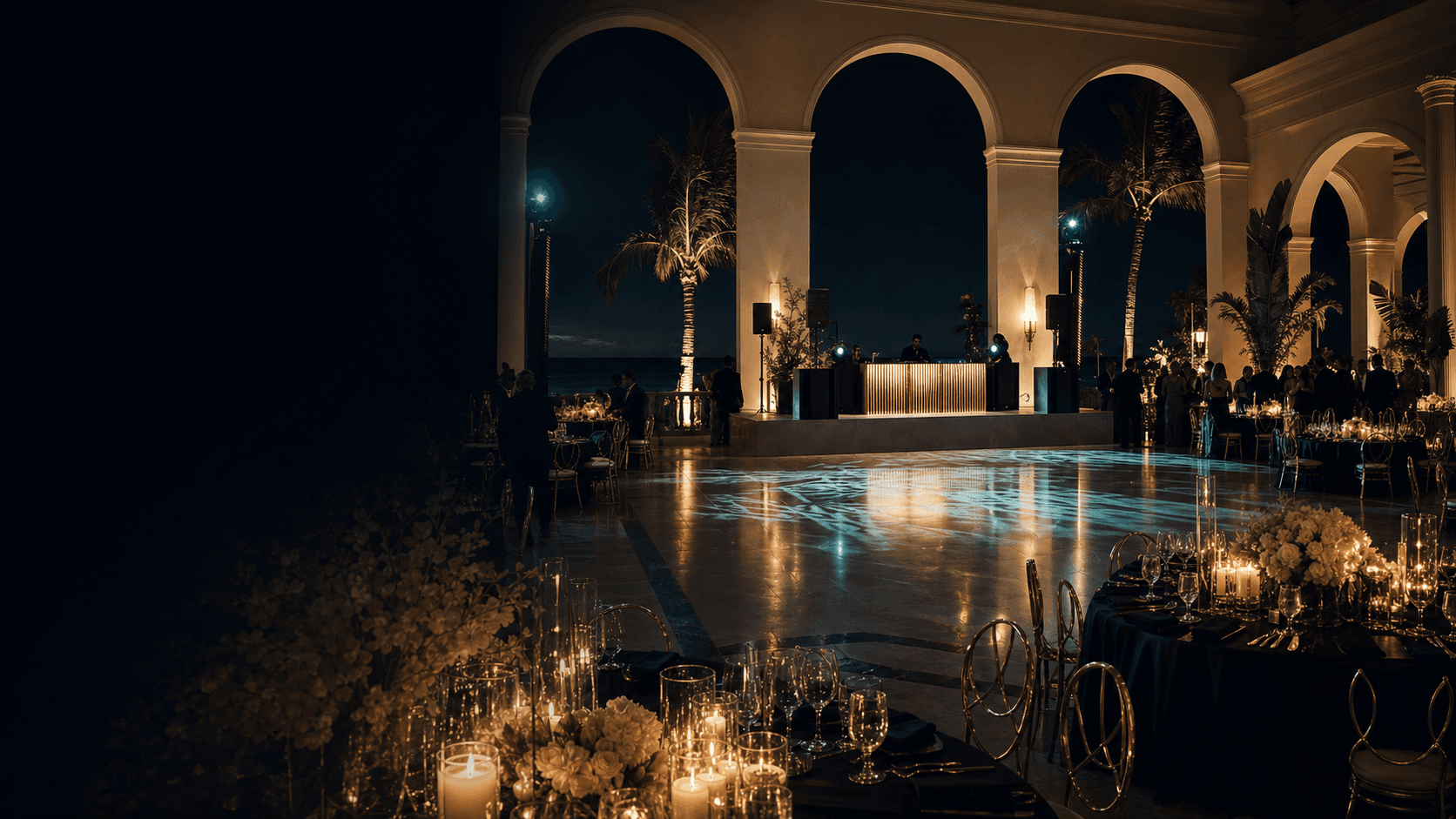 Luxury island ballroom after dark with candlelit tables, a polished dance floor, and DJ production.